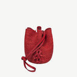 KABE SHOP INC red woven straw bucket bag with a long shoulder strap and decorative tassel detail