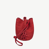 KABE SHOP INC red woven straw bucket bag with a long shoulder strap and decorative tassel detail