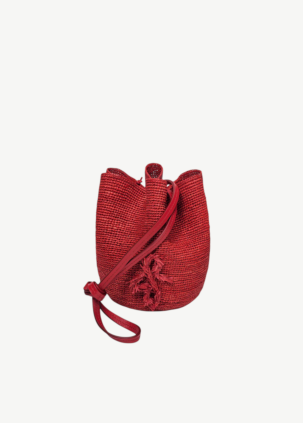 KABE SHOP INC red woven straw bucket bag with a long shoulder strap and decorative tassel detail