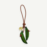 KABE SHOP INC Bag Charm Pea featuring two sculptural green wooden pea pods on a braided brown leather cord with a gold tag