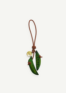 KABE SHOP INC Bag Charm Pea featuring two sculptural green wooden pea pods on a braided brown leather cord with a gold tag