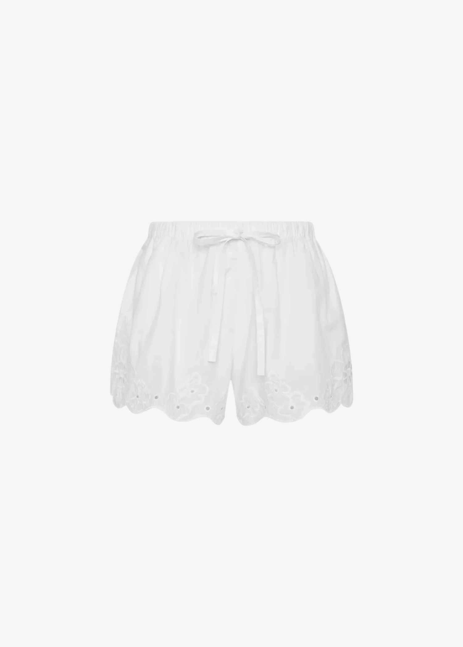 Klara Mini Short in white with an elastic, drawstring-adjustable waistband and a scalloped hem featuring floral cut-out embroidery.
