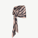 The Souk Skirt, featuring beige and black stripes, is wrapped and knotted at the waist as it drapes elegantly to one side against a plain white background.