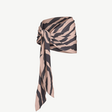 The Souk Skirt, featuring beige and black stripes, is wrapped and knotted at the waist as it drapes elegantly to one side against a plain white background.