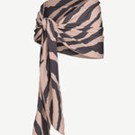 The Souk Skirt, featuring beige and black stripes, is wrapped and knotted at the waist as it drapes elegantly to one side against a plain white background.