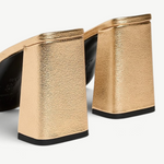 Sloane Heel metallic gold mules with block heels and black outsoles in a timeless silhouette.