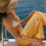 KABE SHOP INC Casa Pant in yellow organic cotton with white crochet detailing worn by a woman on a boat