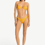 Model wearing KABE SHOP INC Sonali Brief, a textured mustard yellow bikini bottom with side loop tie details.