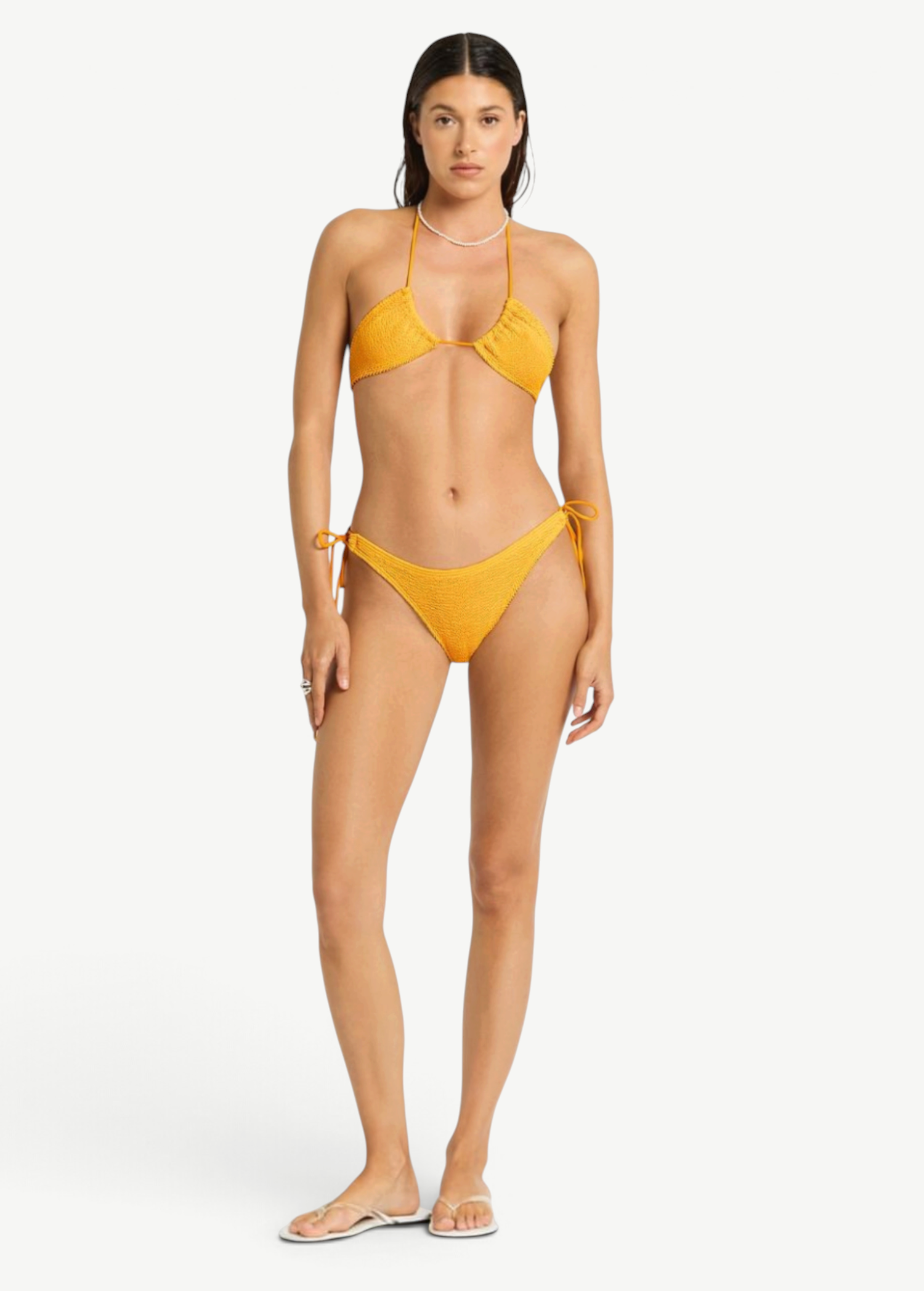 Model wearing KABE SHOP INC Sonali Brief, a textured mustard yellow bikini bottom with side loop tie details.