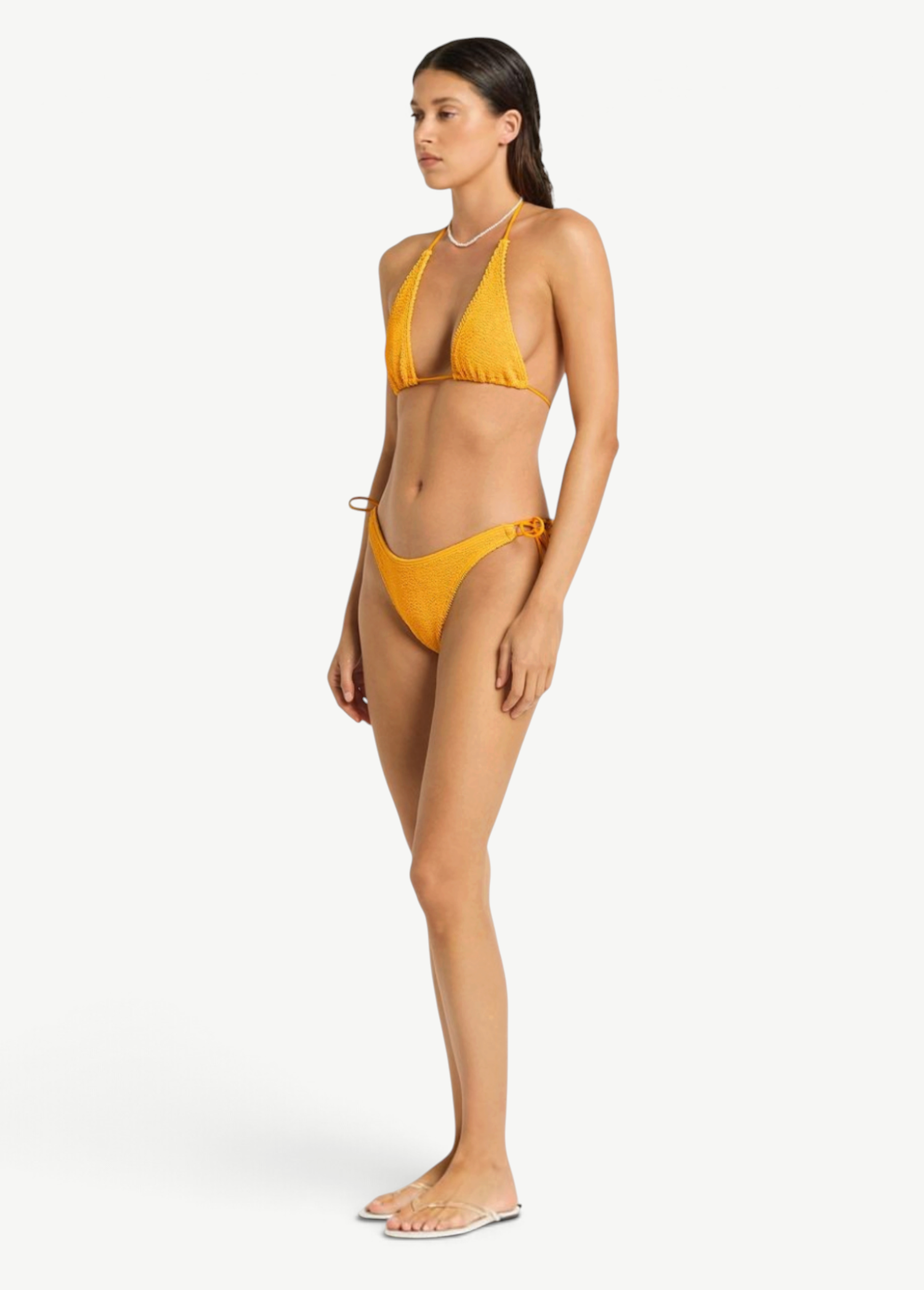 Model wearing KABE SHOP INC yellow textured bikini bottom with side loop tie detail, side view
