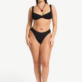 Model wearing KABE SHOP INC Olivia black high-cut bikini briefs in shimmer crinkle fabric with full coverage.