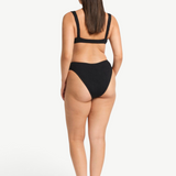 Model wearing KABE SHOP INC Olivia black high-cut bikini brief in shimmer crinkle fabric, back view.