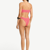 Model wearing KABE SHOP INC Scene Brief pink textured bikini bottom with cheeky coverage and curved waist, back view