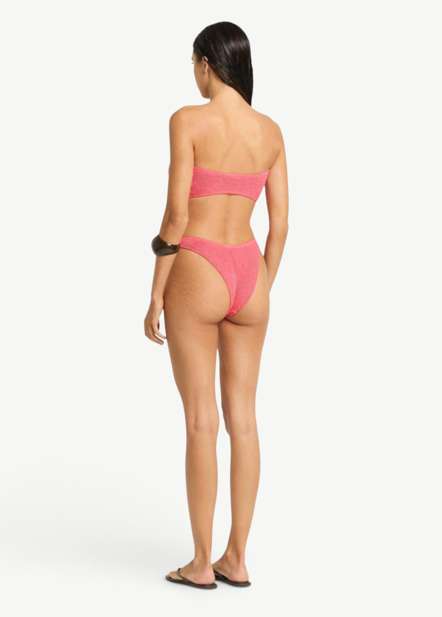 Model wearing KABE SHOP INC Scene Brief pink textured bikini bottom with cheeky coverage and curved waist, back view