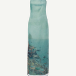 Strapless, floor-length Amara Dress in a sheer, light blue fabric featuring a scenic coastal print of a beach and town, perfect for special occasions.