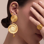 KABE SHOP INC Wixa gold spiral earrings featuring an elongated sculptural design worn by a model with matching rings.