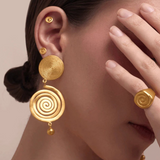KABE SHOP INC Wixa gold spiral earrings featuring an elongated sculptural design worn by a model with matching rings.