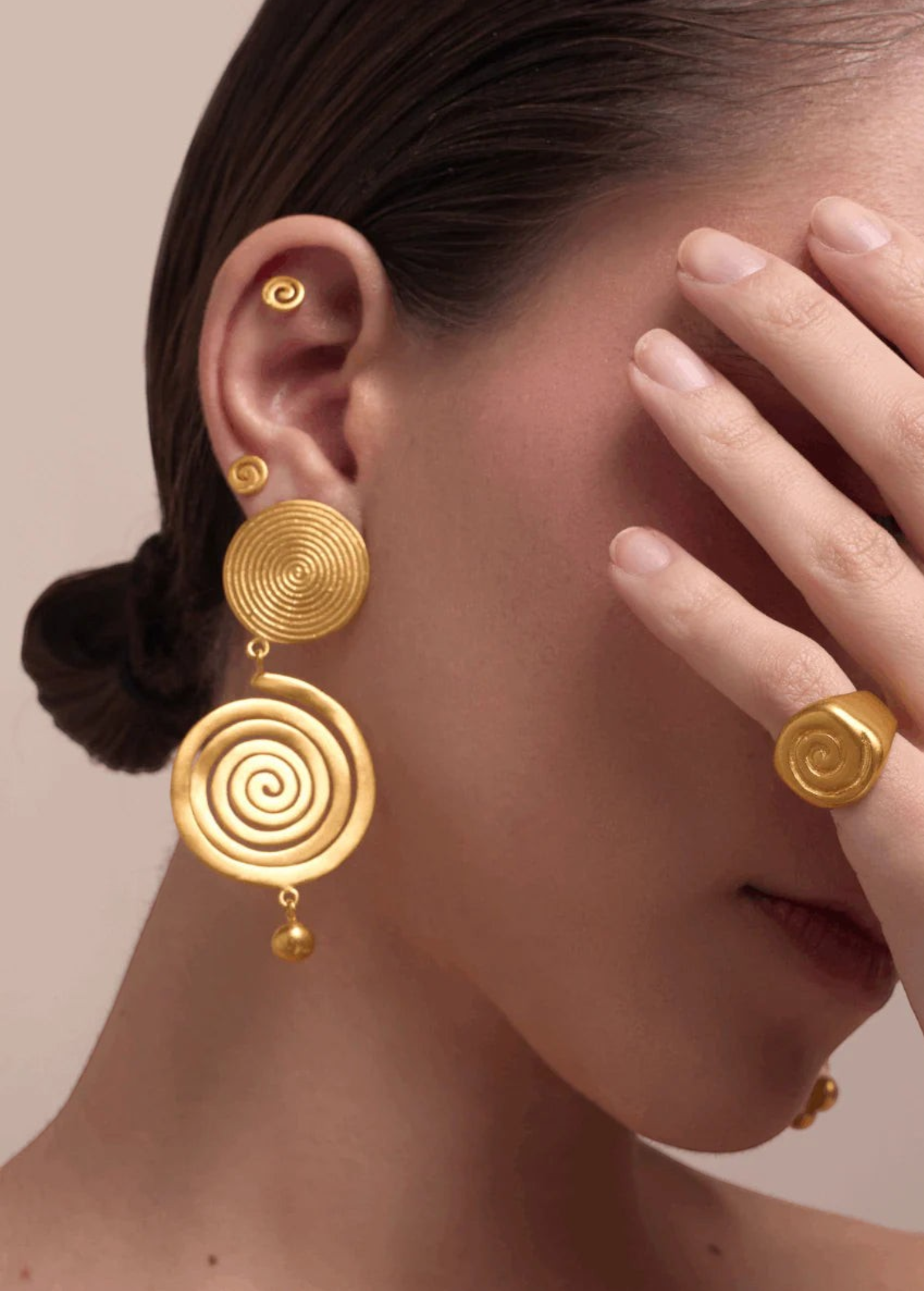 KABE SHOP INC Wixa gold spiral earrings featuring an elongated sculptural design worn by a model with matching rings.